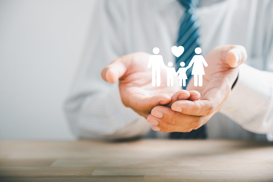 Cupped hands in a striped shirt and tie held beneath an illustrated family group and a heart.